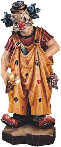 Eine clownartige Figur mit roter Nase, Hut und weiten braunen Gewändern steht auf einem Sockel.