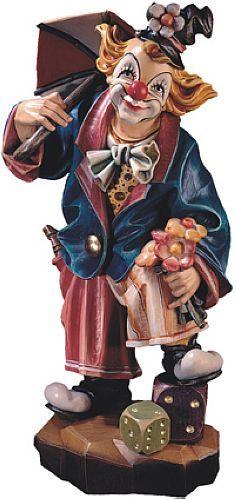 Bunte Clownfigur mit Regenschirm, Blumen und Würfel auf einem Sockel